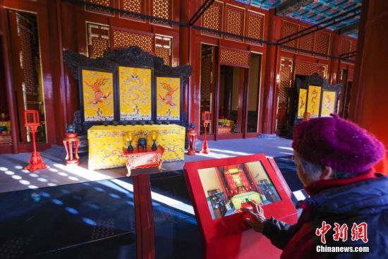 12月6日，游客在北京景山公园寿皇殿内参观电子屏幕上的文物介绍。寿皇殿建筑群始建于明代，清乾隆年间在景山正北重建，建筑仿照太庙规制而建，属中国古代最高等级的建筑形式，是北京中轴线上除故宫外的第二大建筑群。从1955年开始一直由北京市少年宫使用，2016年4月起全面修缮后，于近日向公众免费试运营开放。中新社记者