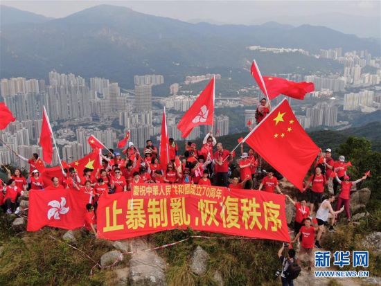 9月14日早上，有百余名香港市民分两批爬上狮子山顶，他们身穿红色T恤，挥舞国旗、区旗，并展示“庆祝中华人民共和国成立70周年”和“止暴制乱，恢复秩序”的横幅。图为市民抵达狮子山顶挥舞国旗、区旗。新华社记者