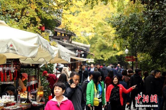 11月20日，游客在成都锦里古街游览。初冬时节，随着天气转冷，成都街头的银杏树叶渐渐变成金黄。中新社记者