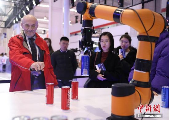 11月21日，首届世界5G大会在北京举行。图为通过5G技术将传感器与机械手臂相连接，能够让机械手臂实时模拟人的手部动作，一名参观者在体验“隔空取物”。中新社记者
