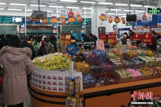1月23日，武汉市民佩戴口罩，在超市购买水果蔬菜、生活用品等物资。中新社记者