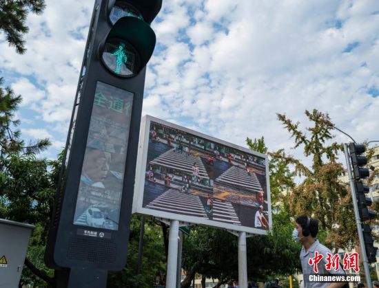 9月15日，位于北京市中关村大街和丹棱街交叉口的智能交通系统正在运行。近日，一套智能交通系统在此地上线试运行，伴随路口红绿灯的转换，行人通行用的信号灯灯杆会发出语音提示，如有行人闯红灯，系统会发出语音警告，闯灯者的面部会被抓拍，呈现在灯杆的屏幕和路边的大屏幕上。