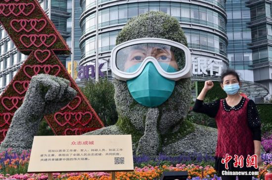 9月26日，市民在北京西单路口西南角《众志成城》国庆主题花坛前拍照留念。