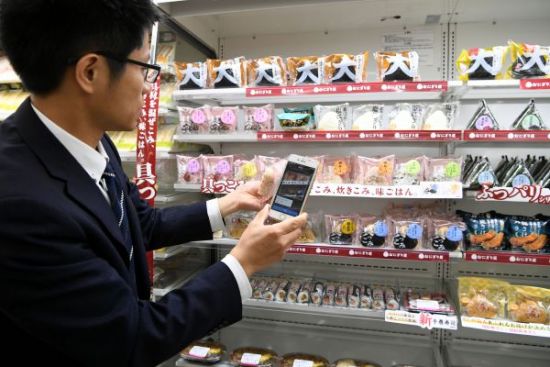 4月23日，在日本东京罗森集团一家便利店，工作人员演示手机自助扫码结帐。
