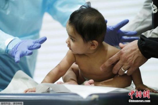 资料图：美国格雷格·古尔布兰森医生对一名婴儿进行常规检查。