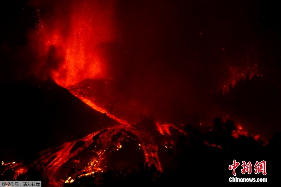当地时间9月19日，西班牙拉帕尔马岛发生火山喷发，滚滚岩浆顺山而下。图为喷涌的岩浆照亮夜空。