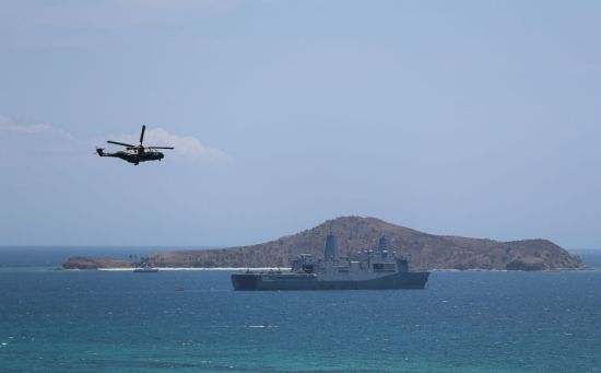 11月14日，在巴布亚新几内亚首都莫尔兹比港，直升机和军舰在海上巡逻。