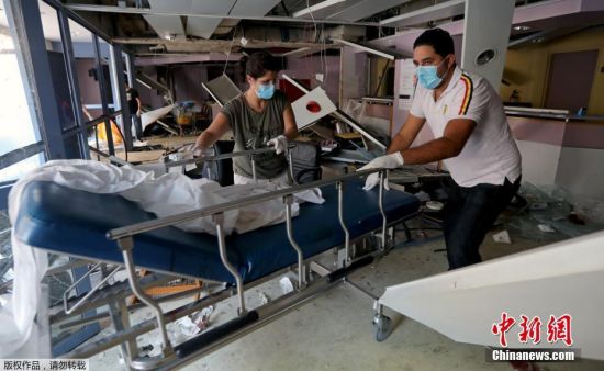 当地时间8月4日晚，黎巴嫩首都贝鲁特港口区发生剧烈爆炸。贝鲁特护士协会主席表示，该市有三家医院被完全摧毁、另有两家医院被部分摧毁。爆炸事件对原本已面临严峻挑战的医院系统，造成了巨大的打击。图为人们在受损的医院内搬动医疗设备。