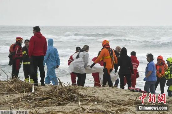 当地时间2023年2月26日，一艘移民船在波涛汹涌的大海中破裂，救援人员在意大利南部库特罗附近的海滩上打捞出一具遇难者遗体。