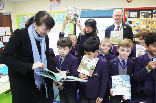 14日，中国凤凰出版传媒集团代表俞慧洵(左)在“中华文化走进英国课堂”活动中，向英国小朋友们讲述中文图书中的故事。　张平