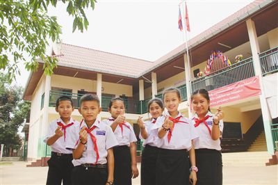 万象农冰村小学的学生们在教学楼前作出“比心”手势，感谢中国的帮助。